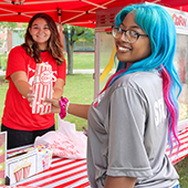 A student volunteer handing out popcorn at a carnival